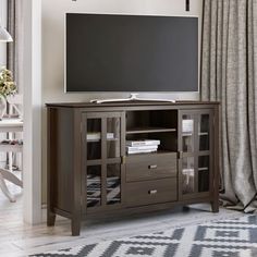 a flat screen tv sitting on top of a wooden entertainment center next to a window