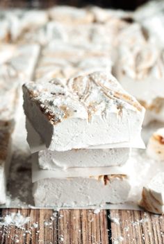 three pieces of white cake sitting on top of a wooden table covered in powdered sugar