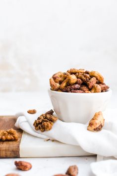 a white bowl filled with nuts on top of a cutting board