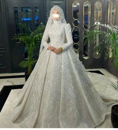 a woman in a white wedding gown standing next to a plant