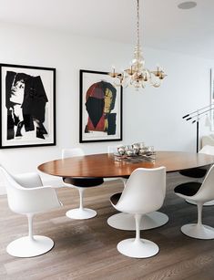 a dining room table with chairs and pictures on the wall