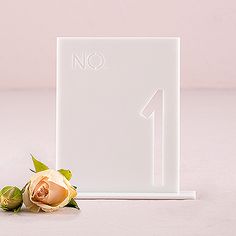 there is a small white sign with a flower on the table next to it that says no 1