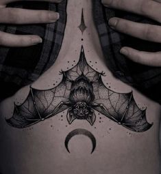 a woman's back with a bat and moon tattoo on her stomach, in black and white