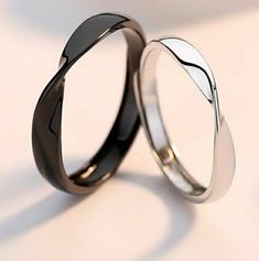 two black and white wedding bands are shown in close up, with one on the other side