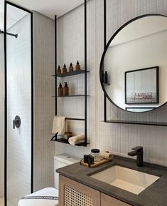 a bathroom with a sink, mirror and shelves on the wall next to the toilet