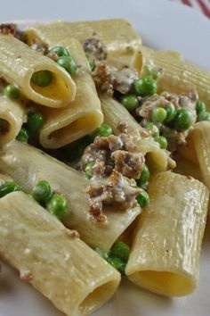 a white plate topped with pasta and peas