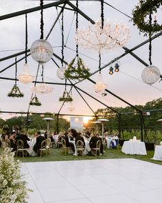 an outdoor wedding reception with chandeliers and disco ball lights hanging from the ceiling