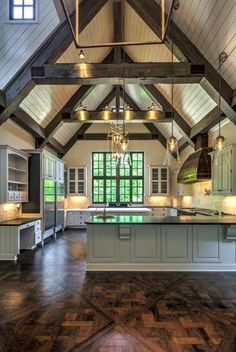 a large open kitchen with wooden floors and vaulted ceilings, along with an island in the middle