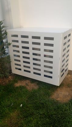 an air conditioner sitting in the grass next to a tree