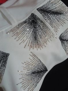 a white shirt with black and gold sequins on it