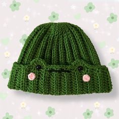 a green knitted hat with buttons on the front and side, against a floral background