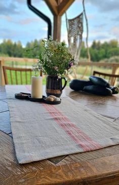 a wooden table topped with a vase filled with flowers next to a candle on top of it