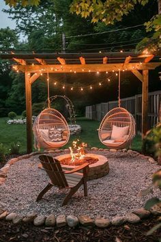 an outdoor patio with two hanging chairs and a fire pit in the middle of it