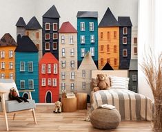 a child's room with colorful houses on the wall and a teddy bear sitting in a chair