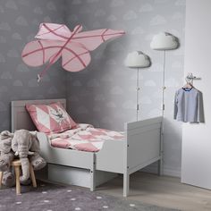 a child's bedroom decorated in pink and grey with an elephant toy hanging from the ceiling