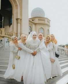 four women dressed in white are standing on some steps