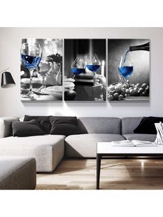 three wine glasses on a table with grapes in the background and one blue glass is being poured