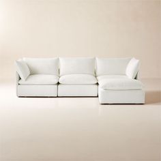 a white couch sitting on top of a floor next to a beige wall and chair