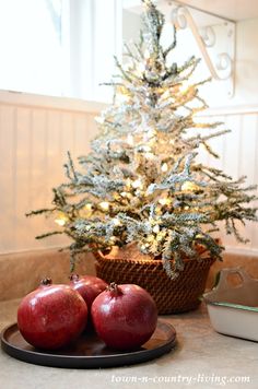 two pomegranates on a plate next to a christmas tree in a basket