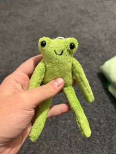 a hand holding a small green stuffed animal