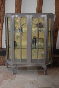 a glass cabinet sitting on top of a stone floor