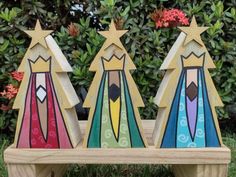 three wooden christmas trees sitting on top of a bench