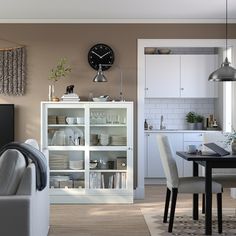 a living room filled with furniture and a clock mounted to the side of a wall