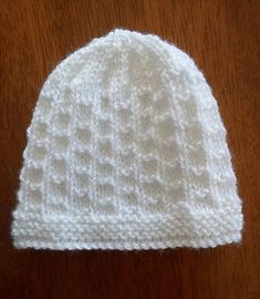 a white knitted hat sitting on top of a wooden table