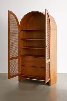 an open wooden bookcase with its doors opened and shelves on the bottom, in front of a white wall