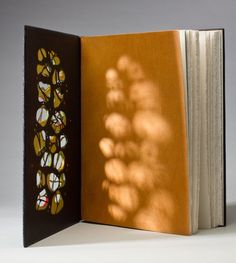 an open book with stained glass designs on the front and back cover, sitting on a white surface