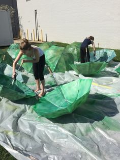 two women are working on some green umbrellas