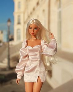 a barbie doll is walking down the street with her hair blowing in the wind and wearing a pink dress