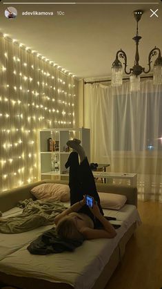 two people laying on a bed in a room with lights all over the walls and floor