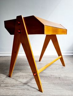 a wooden desk sitting on top of a hard wood floor next to a white wall