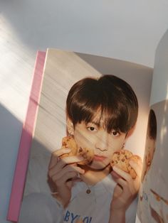 a young boy holding two cookies in front of his face