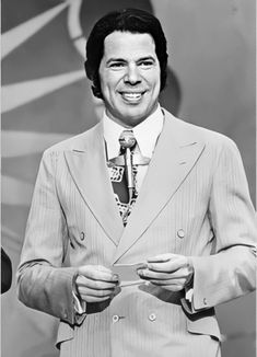 a black and white photo of a man in a suit holding a piece of paper