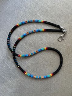 a multicolored beaded necklace on a white cloth with a silver clasp and black cord