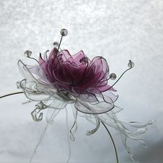 a purple flower sitting on top of a glass vase