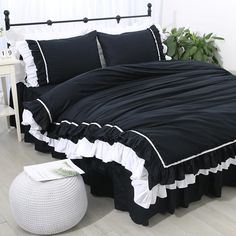 black and white bedding with ruffled edges on a wooden floor next to a potted plant