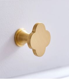 a close up of a gold door handle on a white wall with a flower design