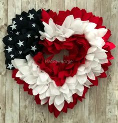 an american flag wreath is hanging on a wooden wall with red, white and blue ruffles