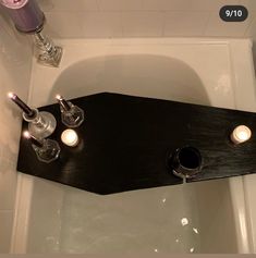 a bathtub with two candles on the side and soap dispenser above it