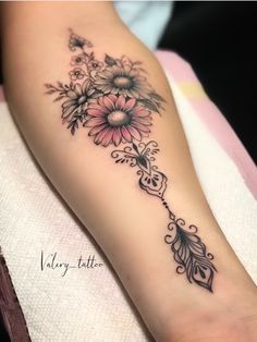 a woman's foot with flowers and an arrow tattoo on her left calf sleeve