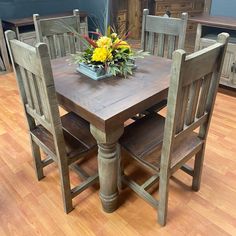 a wooden table with four chairs and a flower centerpiece on top of the table