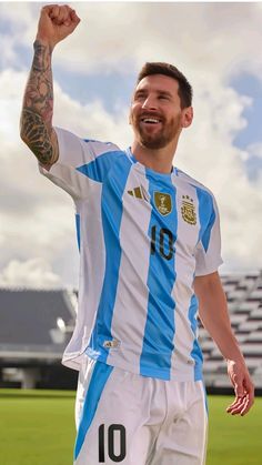 a man in a blue and white soccer uniform holding his fist up while standing on a field