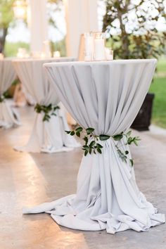 the table is set with white linens and greenery for an elegant wedding reception