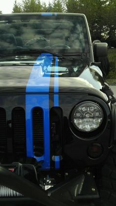 the front end of a black jeep with blue stripes