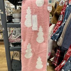 a pink and white teddy bear towel hanging on a rack in a store with other items