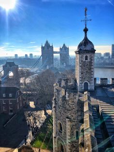 an old tower with a clock on it near the water and bridge in the background