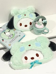 two stuffed animals sitting next to each other on a table with a book and cup